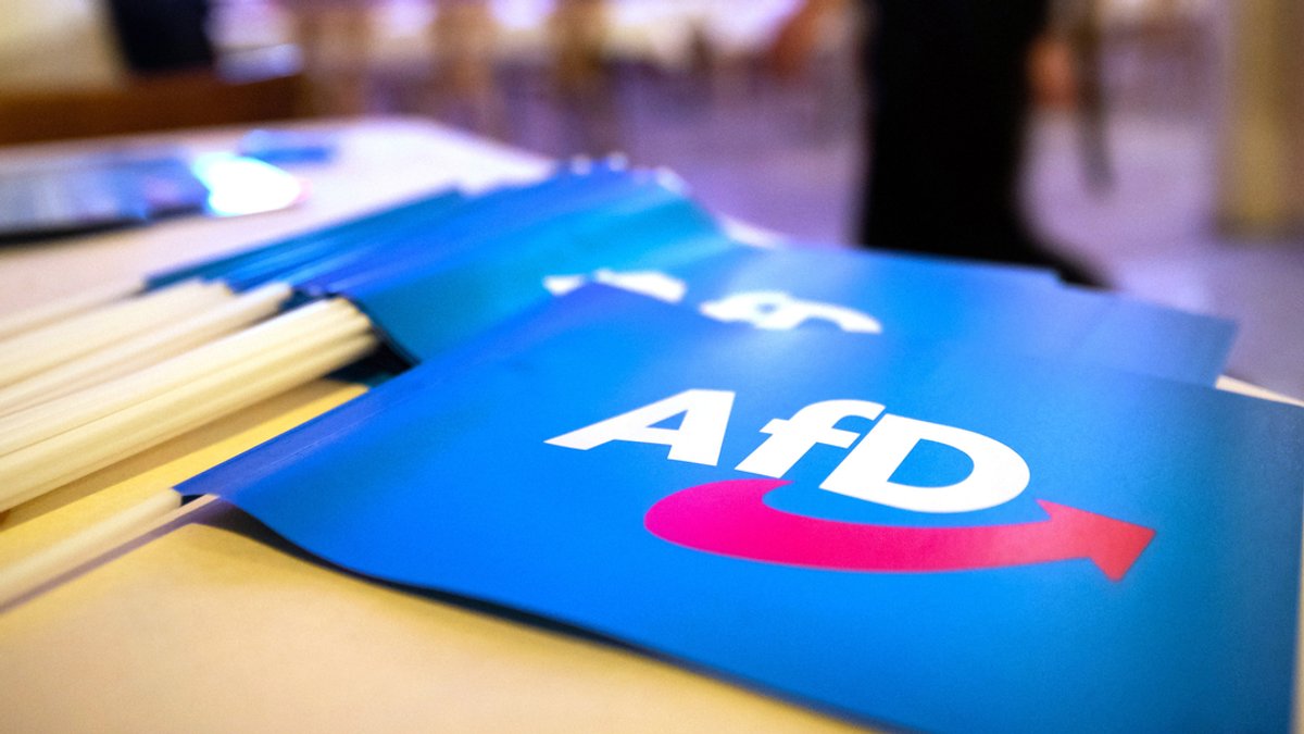 Fähnchen mit dem Logo der AfD liegen beim Landesparteitag der AfD Bayern auf einem Tisch.