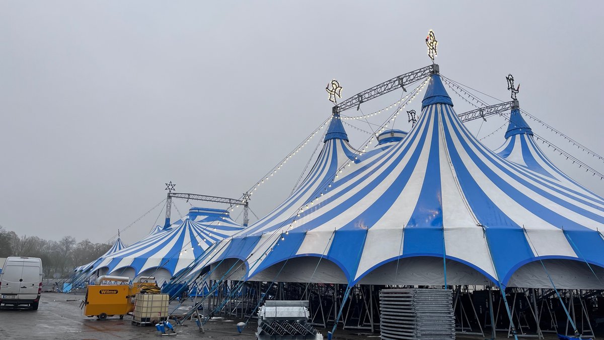 Zwei blau-weiß gestreifte Zirkuszelte stehen auf einem Platz