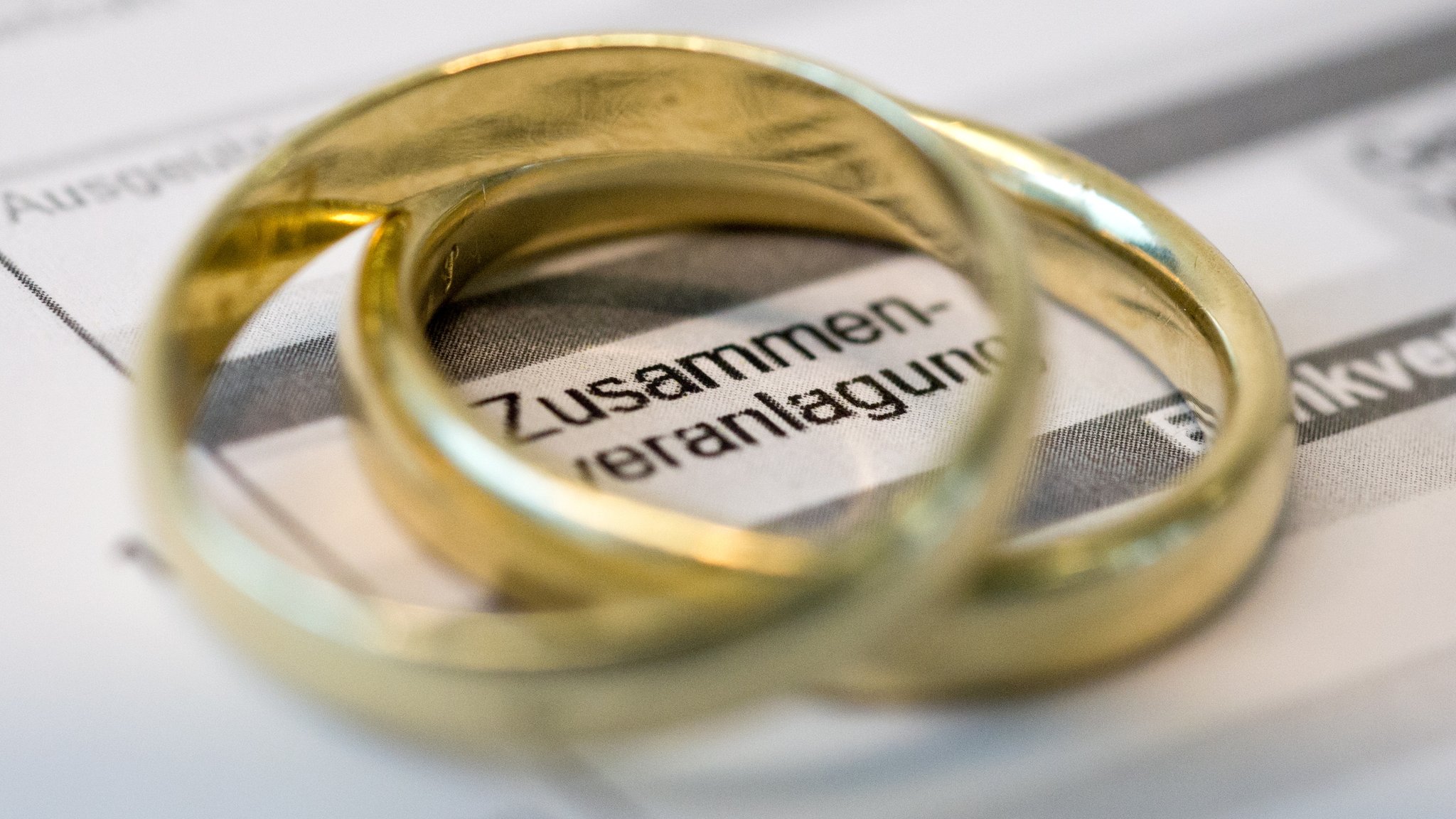 Goldene Eheringe liegen auf Formularen für die Steuererklärung.