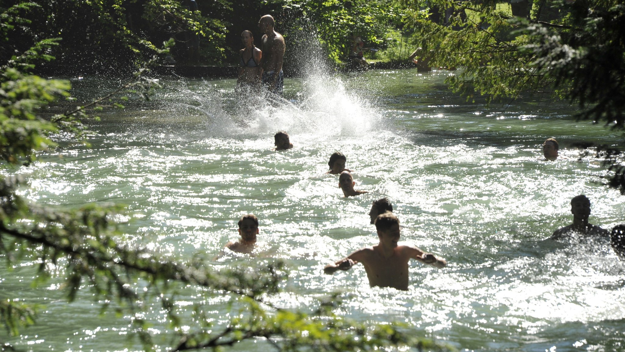 Archivbild: Badende suchen bei hochsommerlichen Temperaturen Abkühlung im Eisbach im Englischen Garten