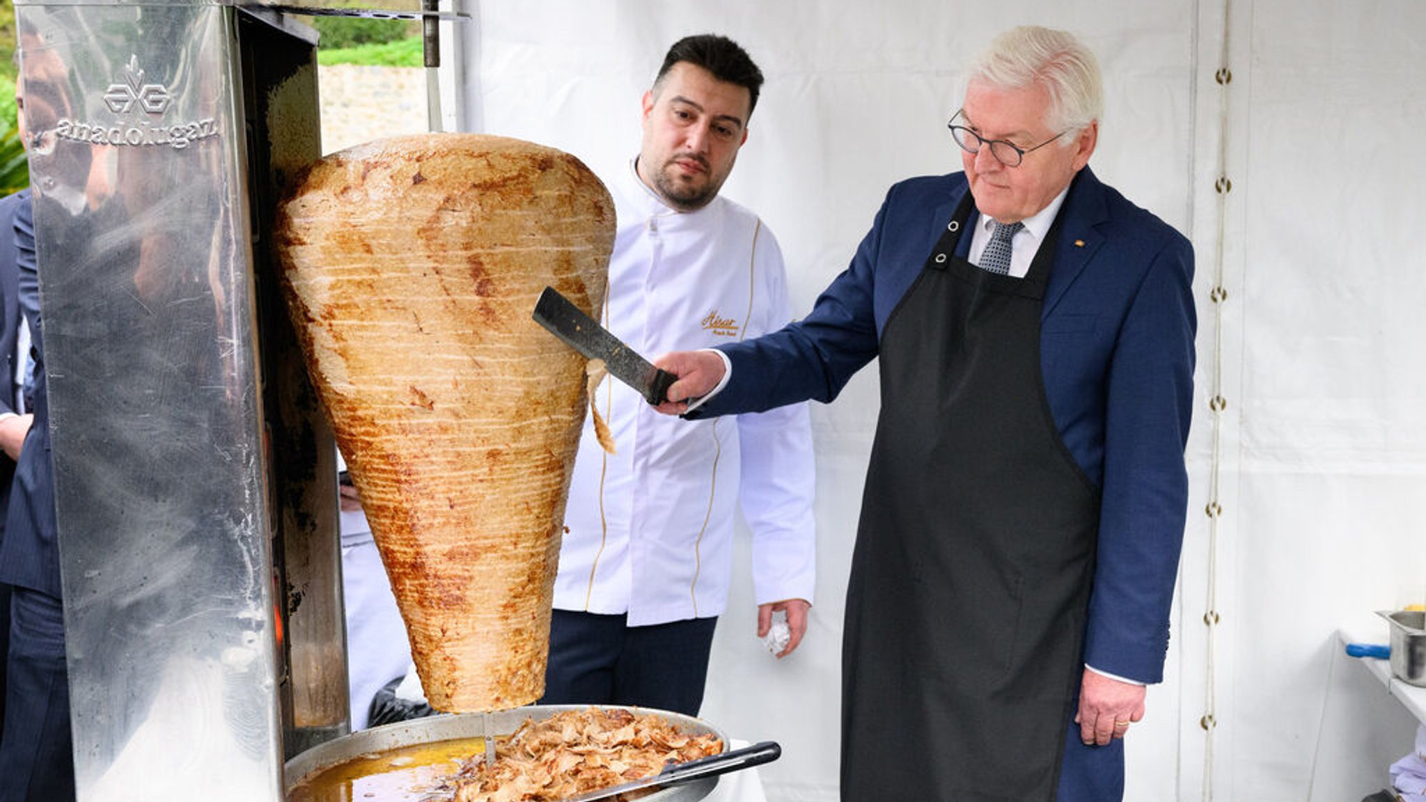 Bundespräsident Frank-Walter Steinmeier (r.) schneidet unter Anleitung des Berliner Gastronoms Arif Keles bei einem Empfang des Bundespräsidenten im Garten der historischen Sommerresidenz des deutschen Botschafters Döner - nach dem Berliner Rezept von Keles.