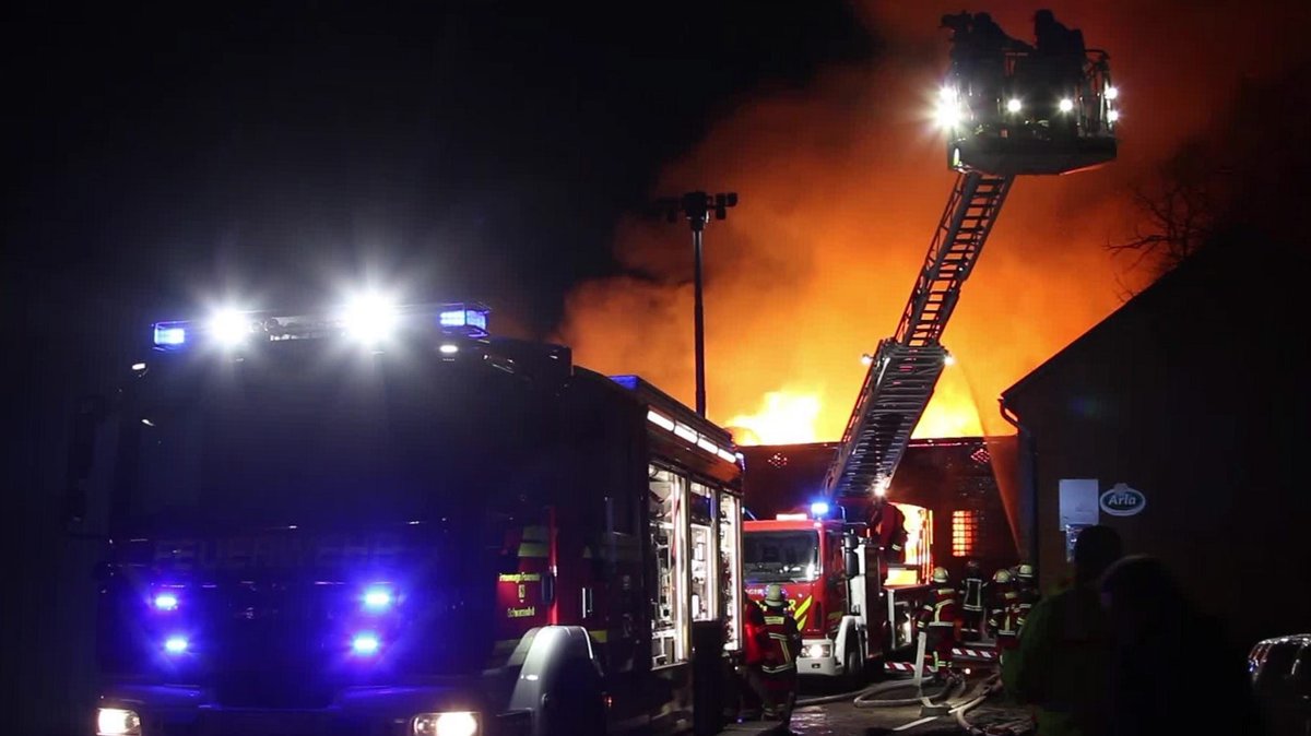 Feuerwehrleute auf Drehleiter löschen nachts einen Brand