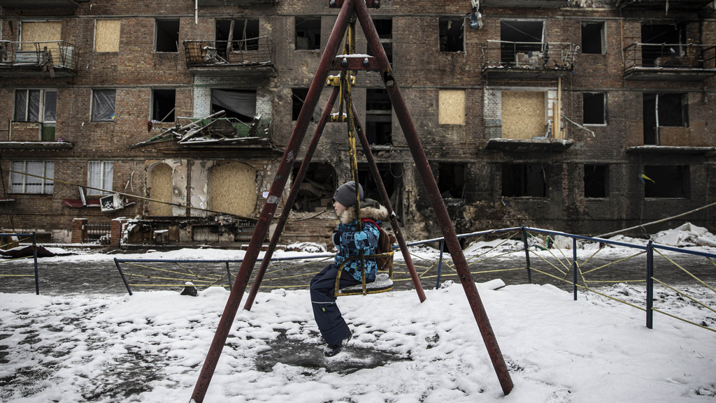 Ein Kind schaukelt vor einer Kriegsruine in Vyshorod in der Ukraine