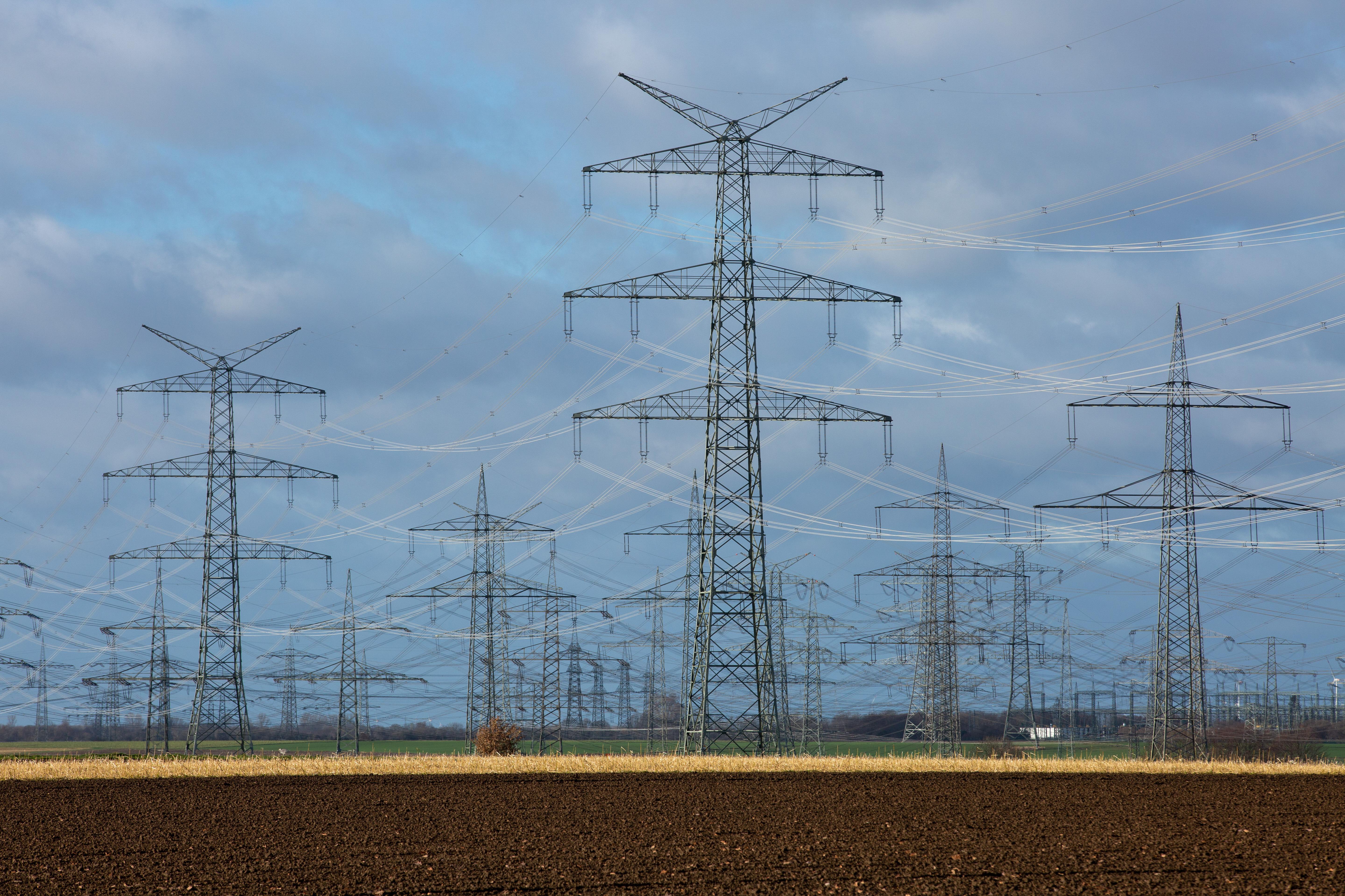 Symbolbild für Supraleitung: Stromleitungen führen zwischen Strommasten über Felder.