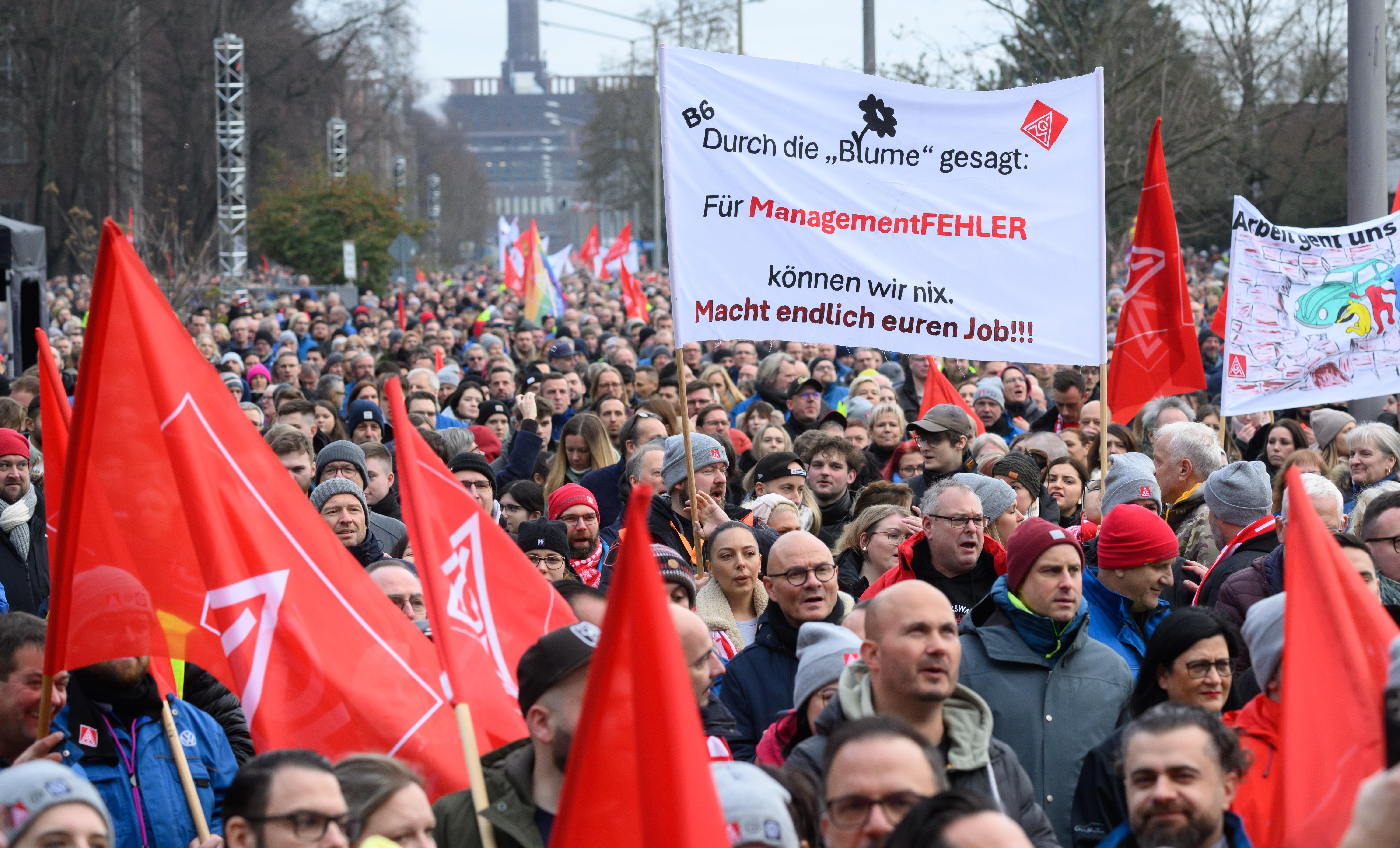 Mitarbeiter von Volkswagen stehen bei einer Streikkundgebung auf dem Gelände vom VW Stammwerk Wolfsburg