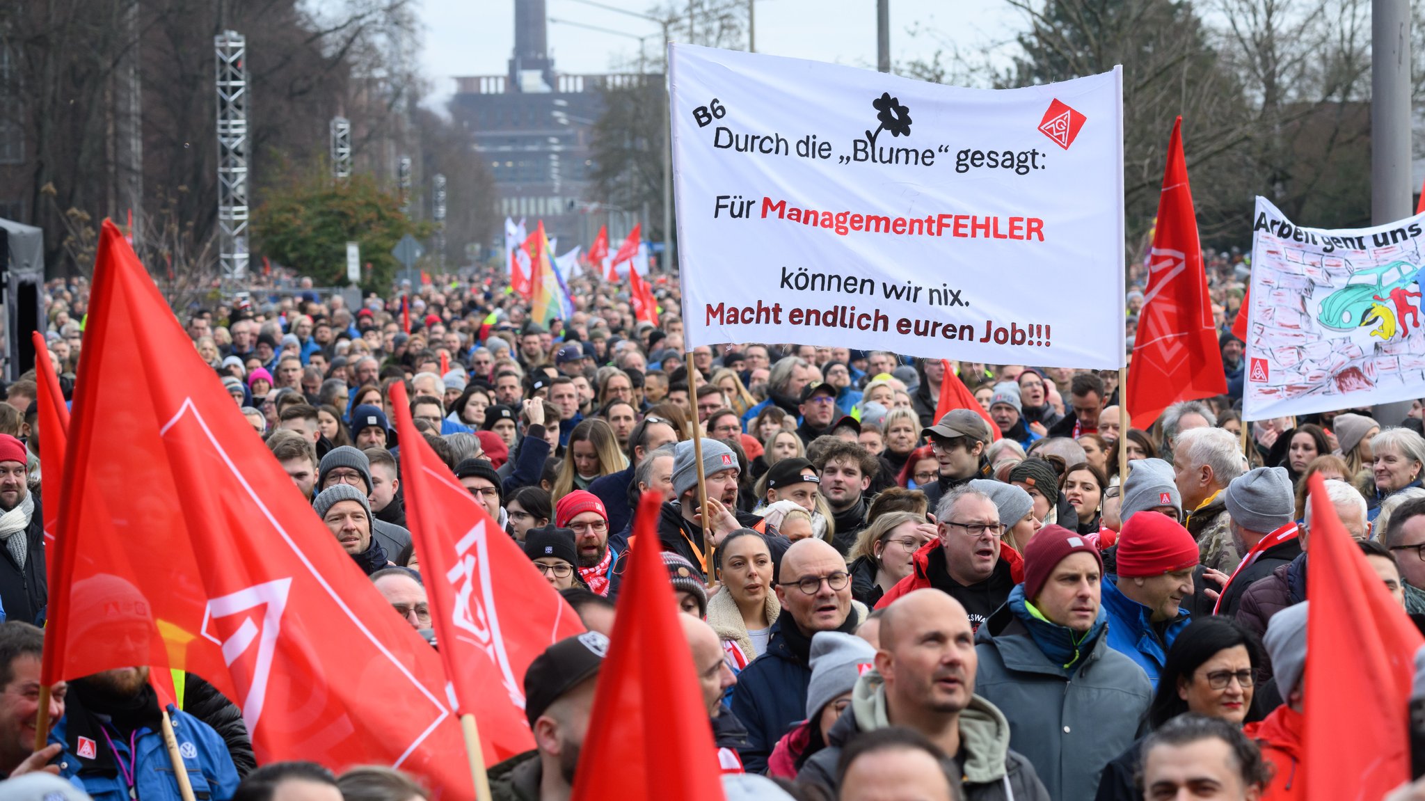 Mitarbeiter von Volkswagen stehen bei einer Streikkundgebung auf dem Gelände vom VW Stammwerk Wolfsburg