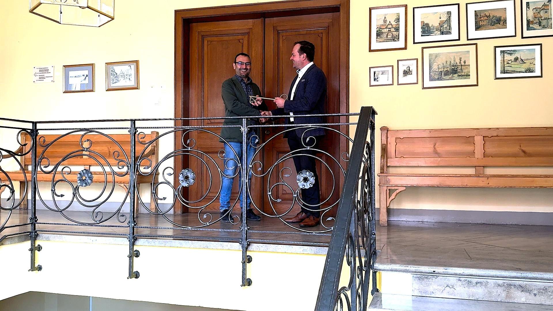 Zwei Männer übergeben einen Schlüssel.