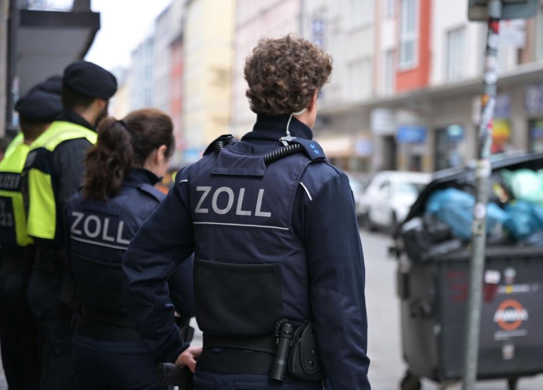 Ein Zollbeamter steht zusammen mit Kollegen an einer Straße im Münchner Bahnhofsviertel