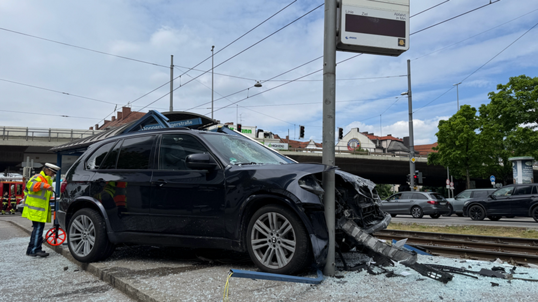 In einem zerstörten Trambahnhäuschen nahe der Donnersberger Brücke in München steht ein BMW, dessen Vorderpartie ebenfalls zerstört ist, umgeben von Scherben. Nach dem tödlichen Unfall an einer Münchner Trambahnhaltestelle werden Forderungen laut, Fußgänger besser zu schützen. | Bild: BR/Ramona Dinauer In einem zerstörten Trambahnhäuschen nahe der Donnersberger Brücke in München steht ein BMW, dessen Vorderpartie ebenfalls zerstört ist, umgeben von Scherben. Nach dem tödlichen Unfall an einer Münchner Trambahnhaltestelle werden Forderungen laut, Fußgänger besser zu schützen.