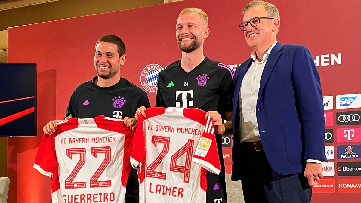 Bayerns Spieler Raphael Guerreiro (l-r) und Konrad Laimer stehen mit ihren neuen Trikots neben Jan-Christian Dreesen, Vorstandsvorsitzender der FC Bayern München AG. 