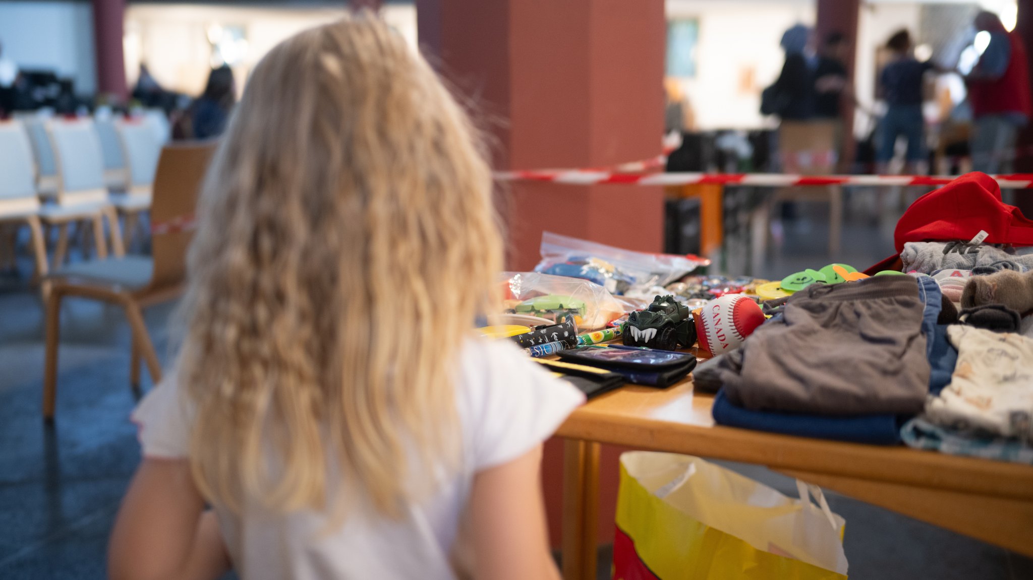 Symbolbild: Ein Mädchen steht während der Ausgabezeit in einer Ausgabestelle der Berliner Tafel an einem Tisch mit Spielzeug.