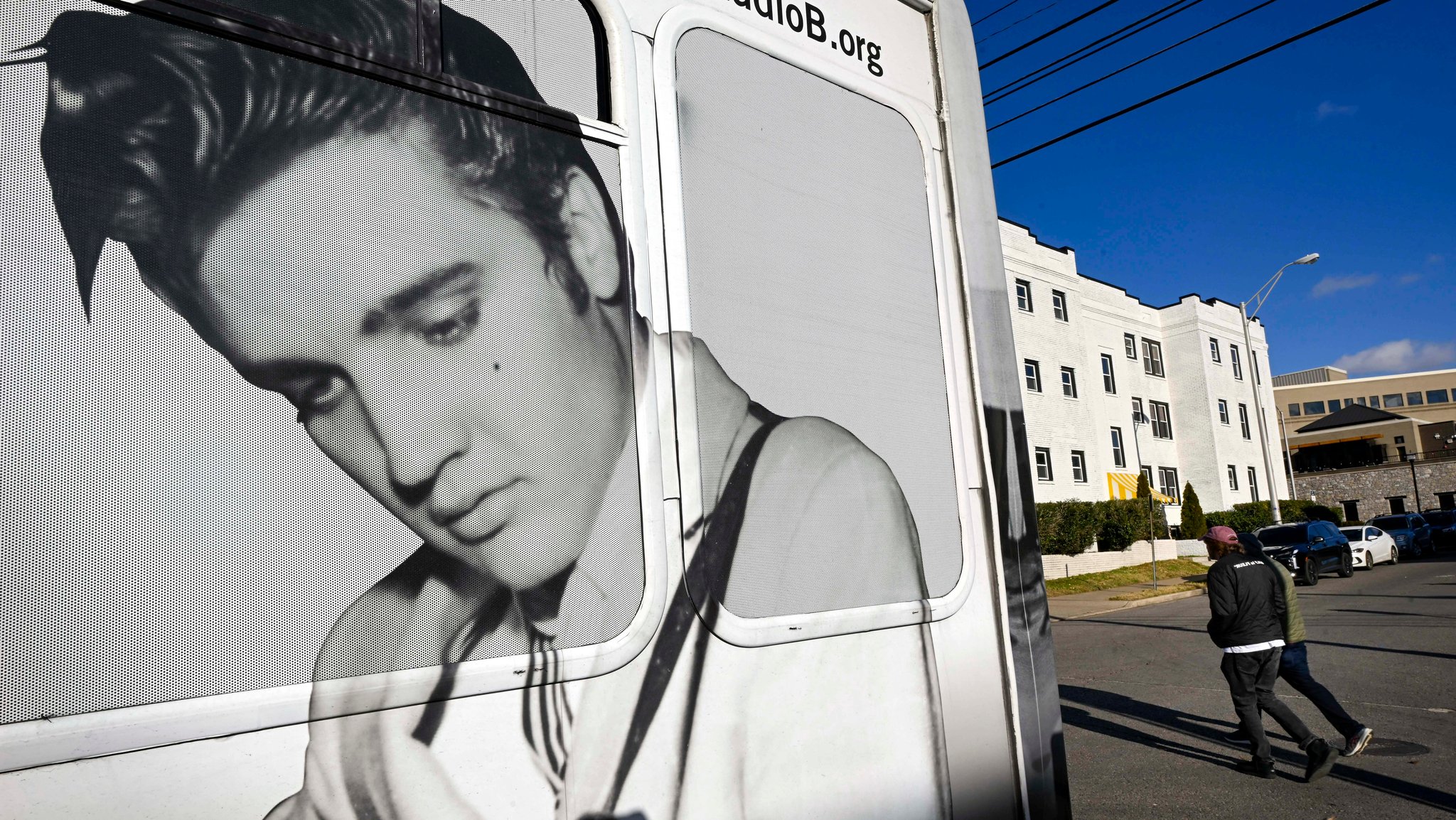 Fußgänger gehen an einem Bus vorbei, auf dem ein Bild von Elvis Presley zu sehen ist.