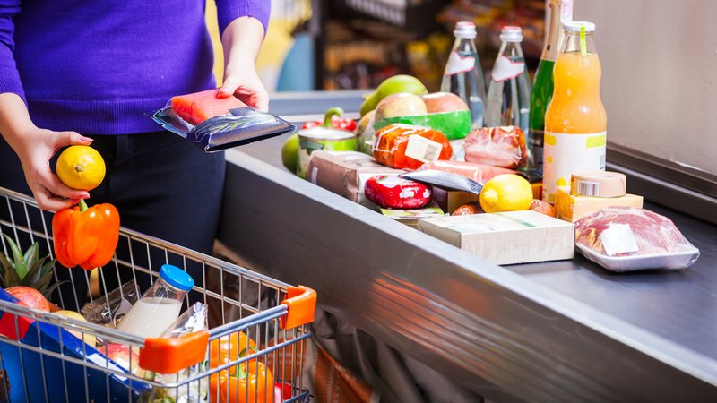 Eine Frau legt Waren aus ihrem Einkaufswagen auf das Kassenband (Symbolbild) | Bild: stock.adobe.com/Andrey Bandurenko Eine Frau legt Waren aus ihrem Einkaufswagen auf das Kassenband (Symbolbild)