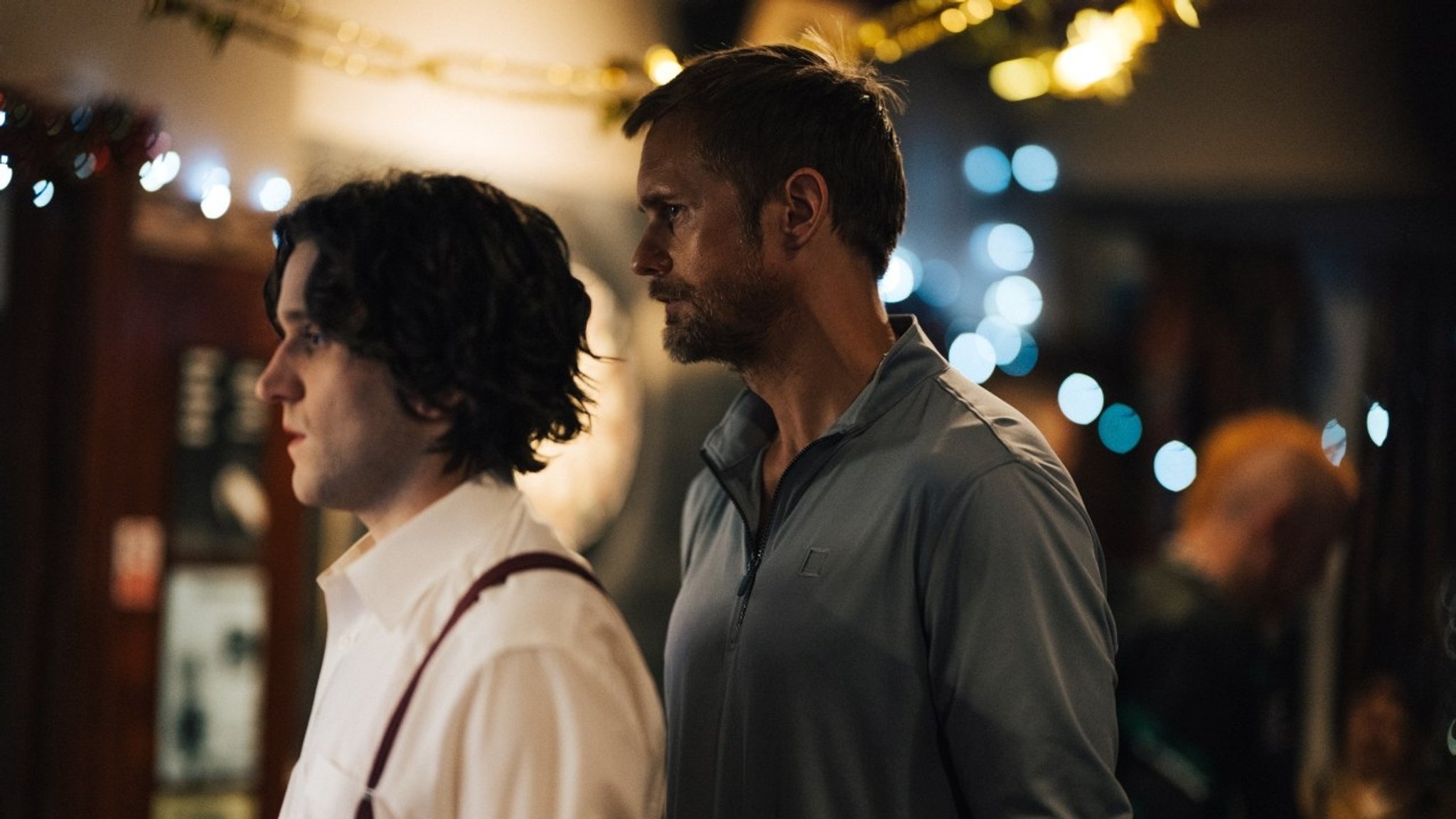 Alexander Skarsgård steht hinter Harry Melling in einer Bar-Szene aus dem Film "Pillion".
