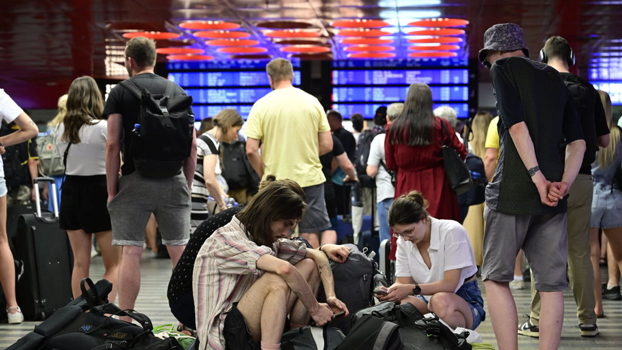 04.07.2025, Tschechien, Praha: Passagiere sitzen in der Halle des Prager Hauptbahnhofs wähtrend eines Stromausfalls.  Ein Stromausfall hat am Freitag große Teile Tschechiens und der Millionenmetropole Prag lahmgelegt. Foto: Vondrou· Roman/CTK/dpa +++ dpa-Bildfunk +++