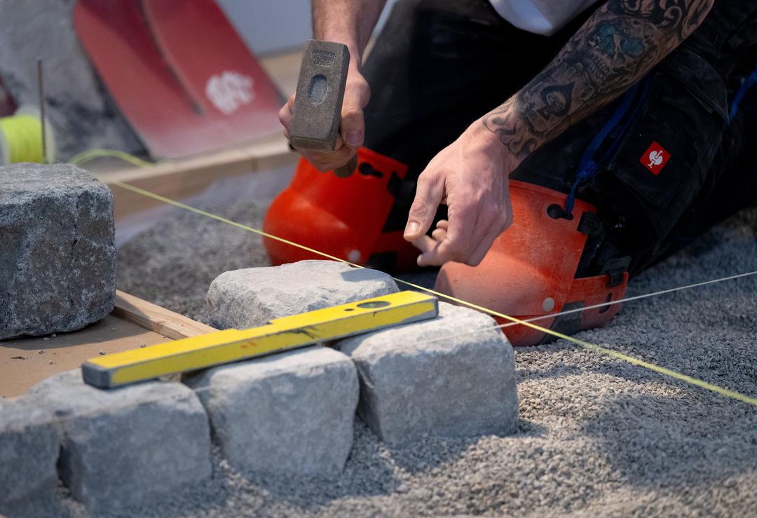 Ein Handwerker verlegt während der Internationalen Handwerksmesse (IHM) an einem Messestand Pflastersteine.