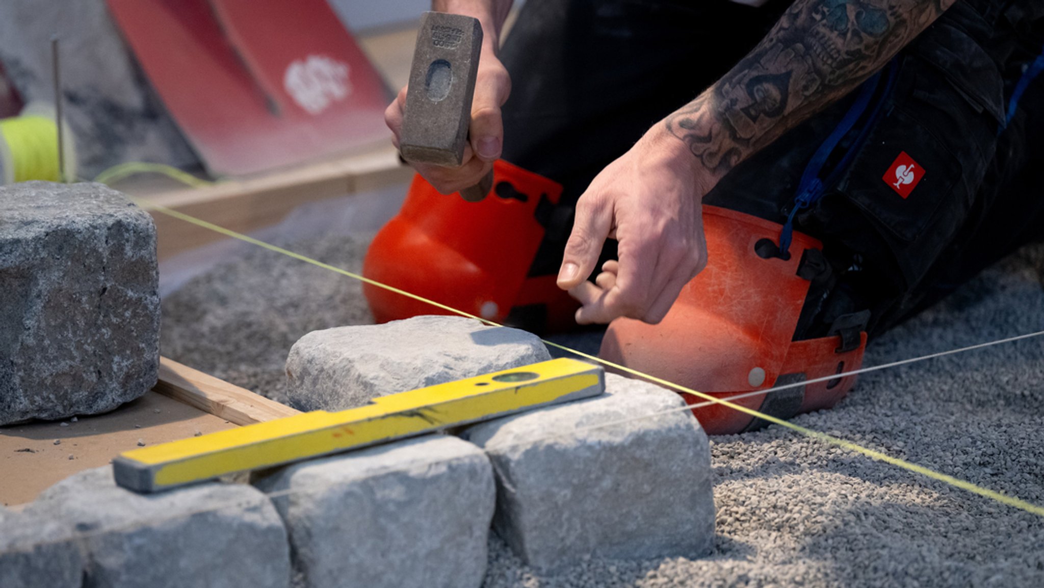 Ein Handwerker verlegt während der Internationalen Handwerksmesse (IHM) an einem Messestand Pflastersteine.