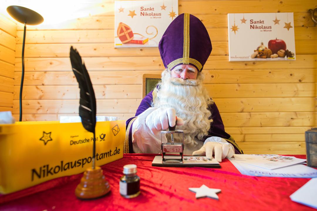ARCHIV - 05.12.2020, Saarland, St. Nikolaus: Der Nikolaus stempelt in der neuen Nikolaushütte, in der sich das Nikolauspostamt befindet, einen Brief ab. Rund 13.000 Briefe wurden bereits beantwortet und verschickt. | Bild:dpa-Bildfunk/Oliver Dietze