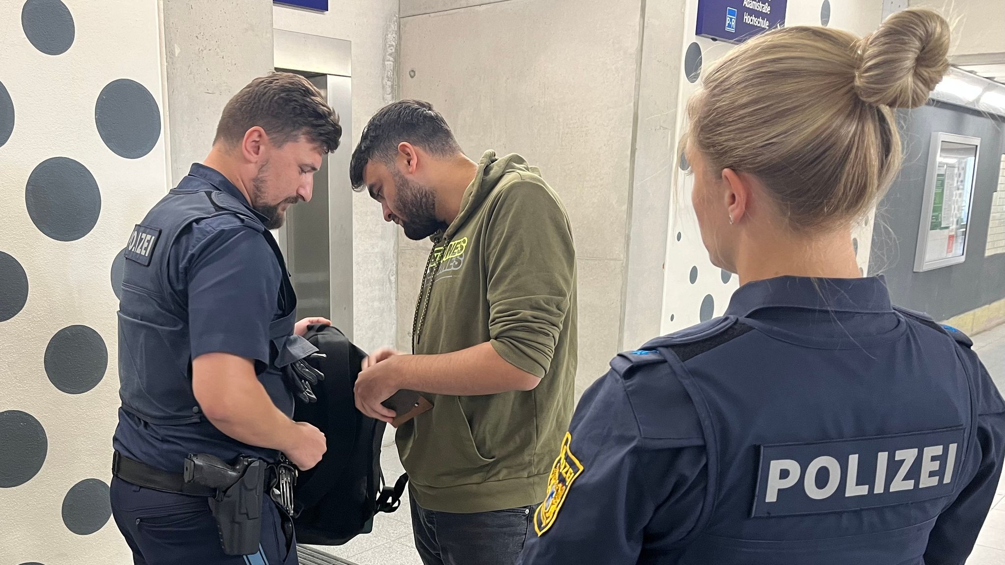 Ein Polizist schaut in den Rucksack eines Mannes 