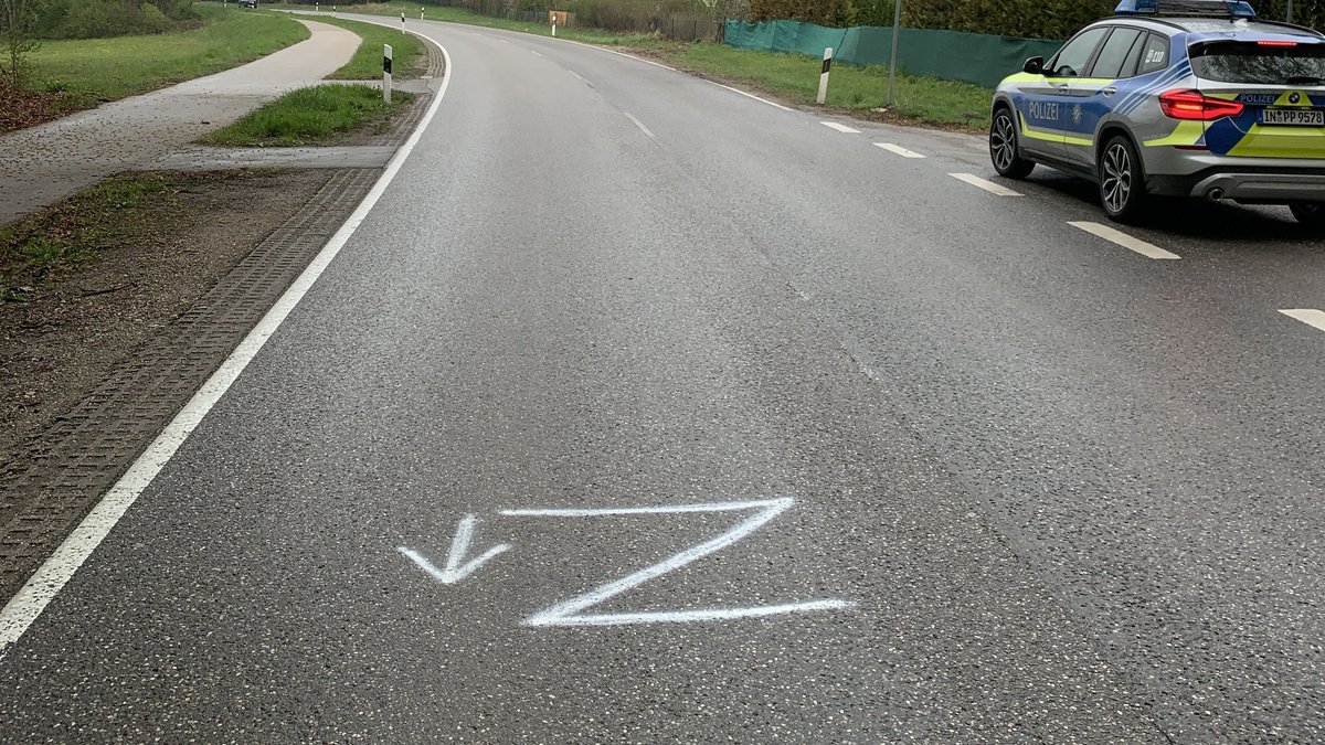 Auf einer Straße ist mit weißer Farbe ein großes "Z" auf den Belag geschrieben. Im Hintergrund steht ein Streifenwagen der Polizei.