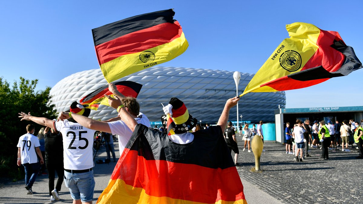 Ein Fußball-Fan mit Deutschland-Flaggen vor dem Münchner Fußball-Stadion