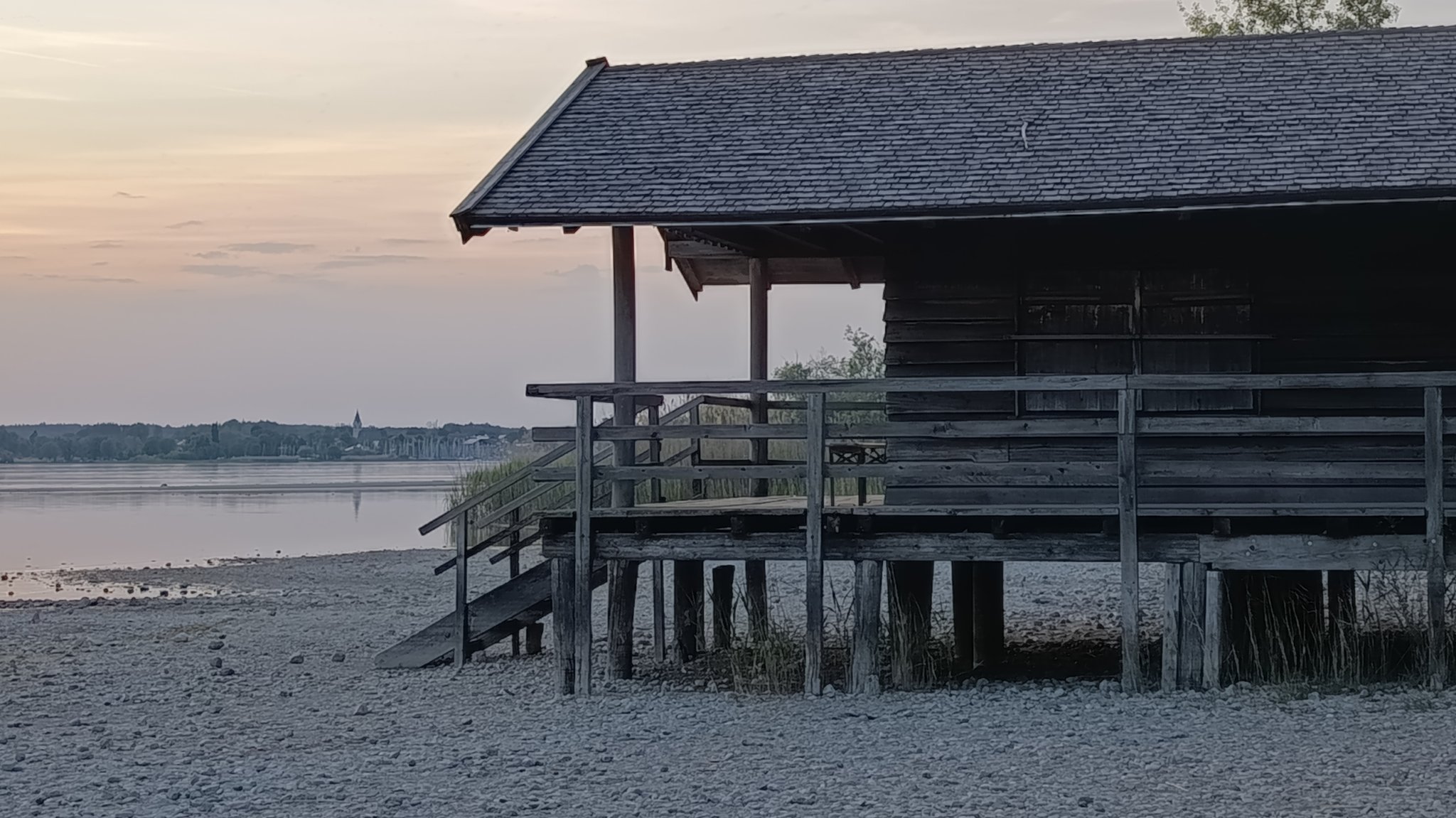 Auswirkung des Niedrigwassers im Chiemsee: Ein Bootshaus in Chieming liegt statt im Wasser auf dem Trockenen im Kiesbett. 