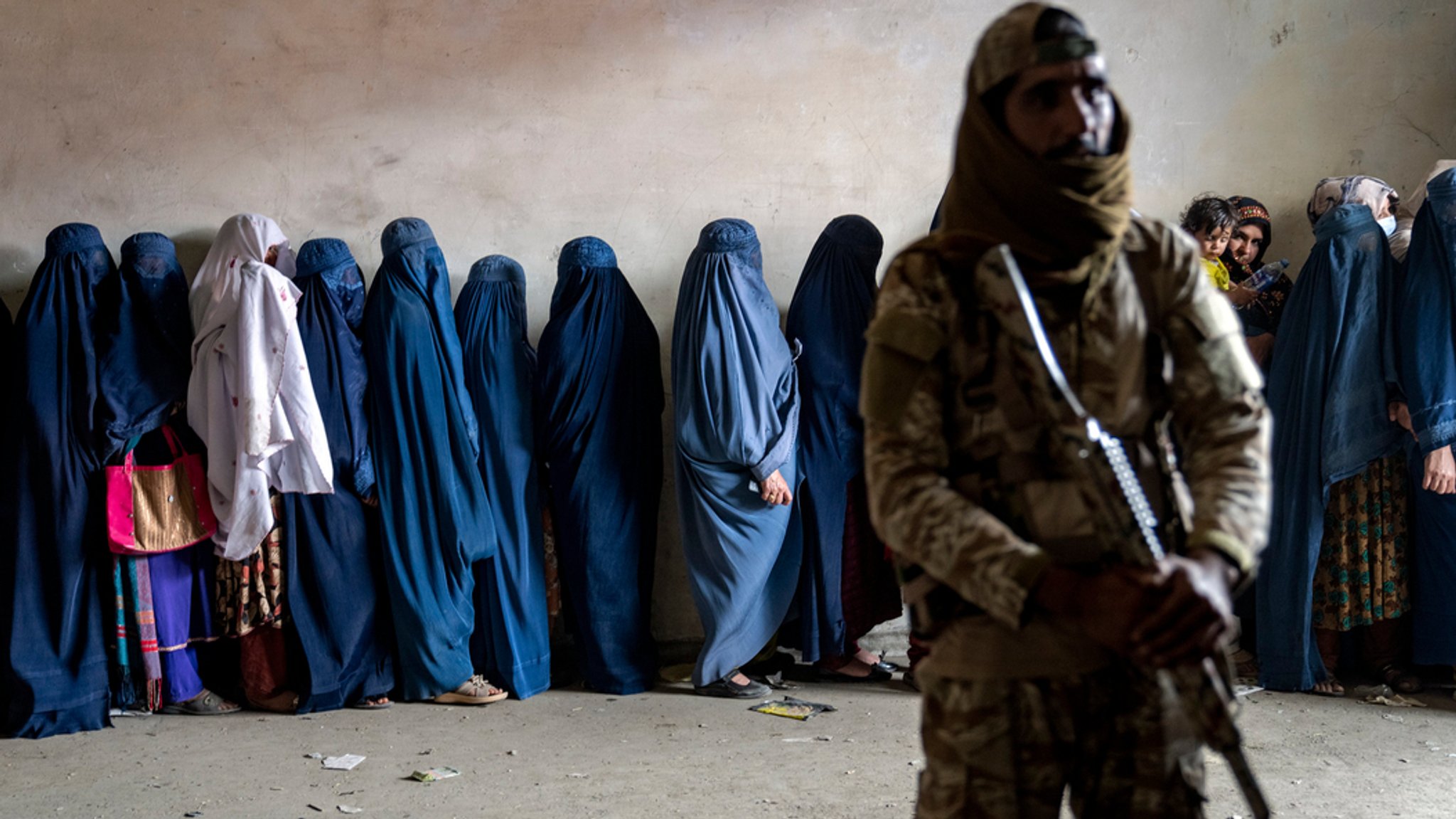 Bewaffneter Mann und im Hintergrund Frauen. 