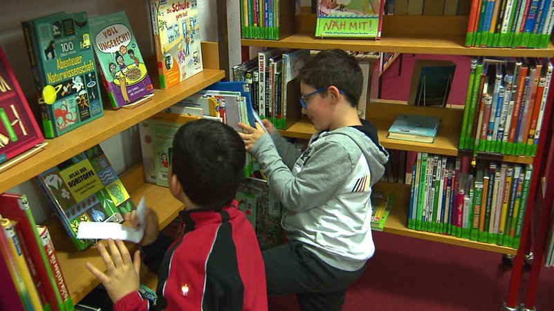 Kinder suchen versteckte Kastanien in einem Bücherregal | Bild: BR Kinder suchen versteckte Kastanien in einem Bücherregal