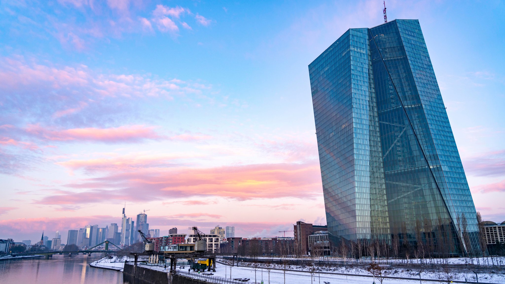 Die EZB vor der winterlichen Skyline von Frankfurt