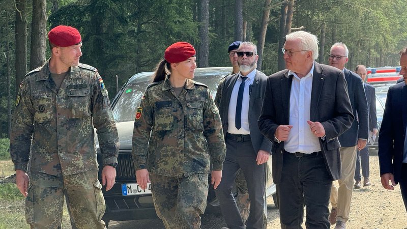 Ein Soldat und eine Soldatin gehen neben dem Bundespräsidenten.