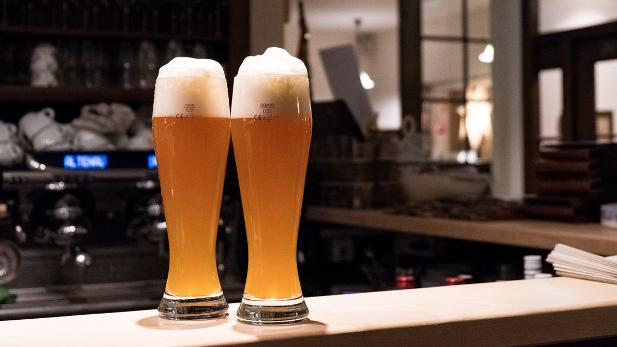 Zwei Gläser mit frisch gezapften Weißbier stehen auf dem Tresen eines traditionellen bayerischen Wirtshaus.