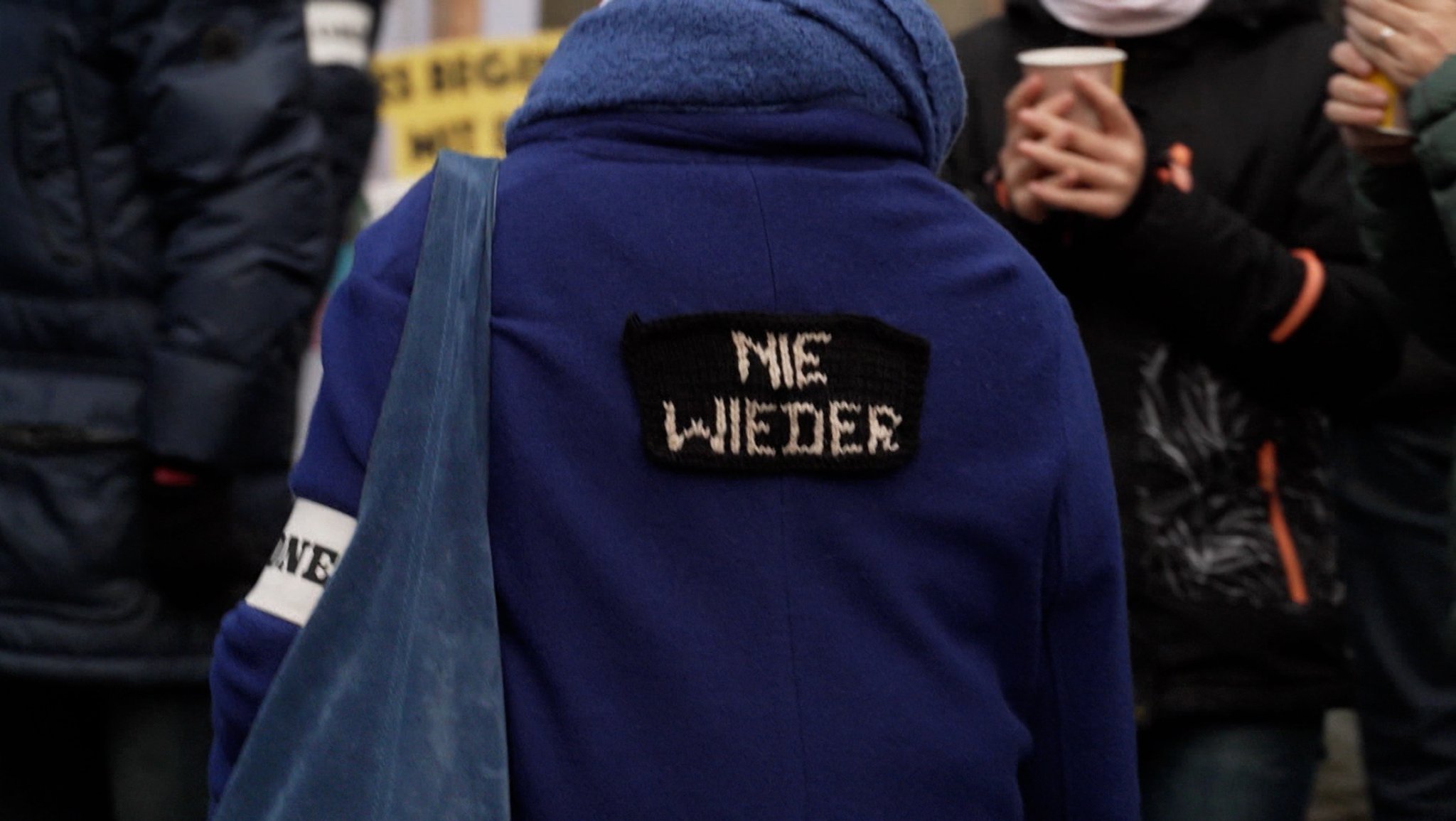 Eine Person trägt eine Jacke, auf deren Rückseite "Nie wieder" zu lesen ist. 