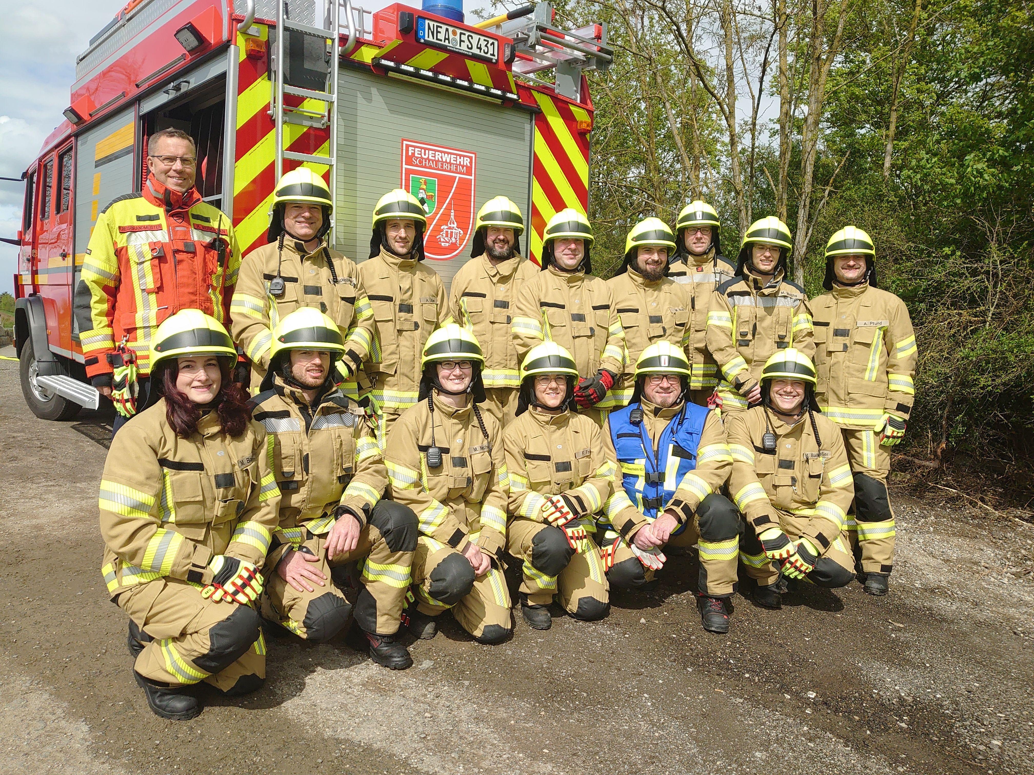Ein Teil der neuen Feuerwehrtruppe in Schauerheim steht und kniet vor dem Löschfahrzeug  mit dem Namen "Wilhelm".