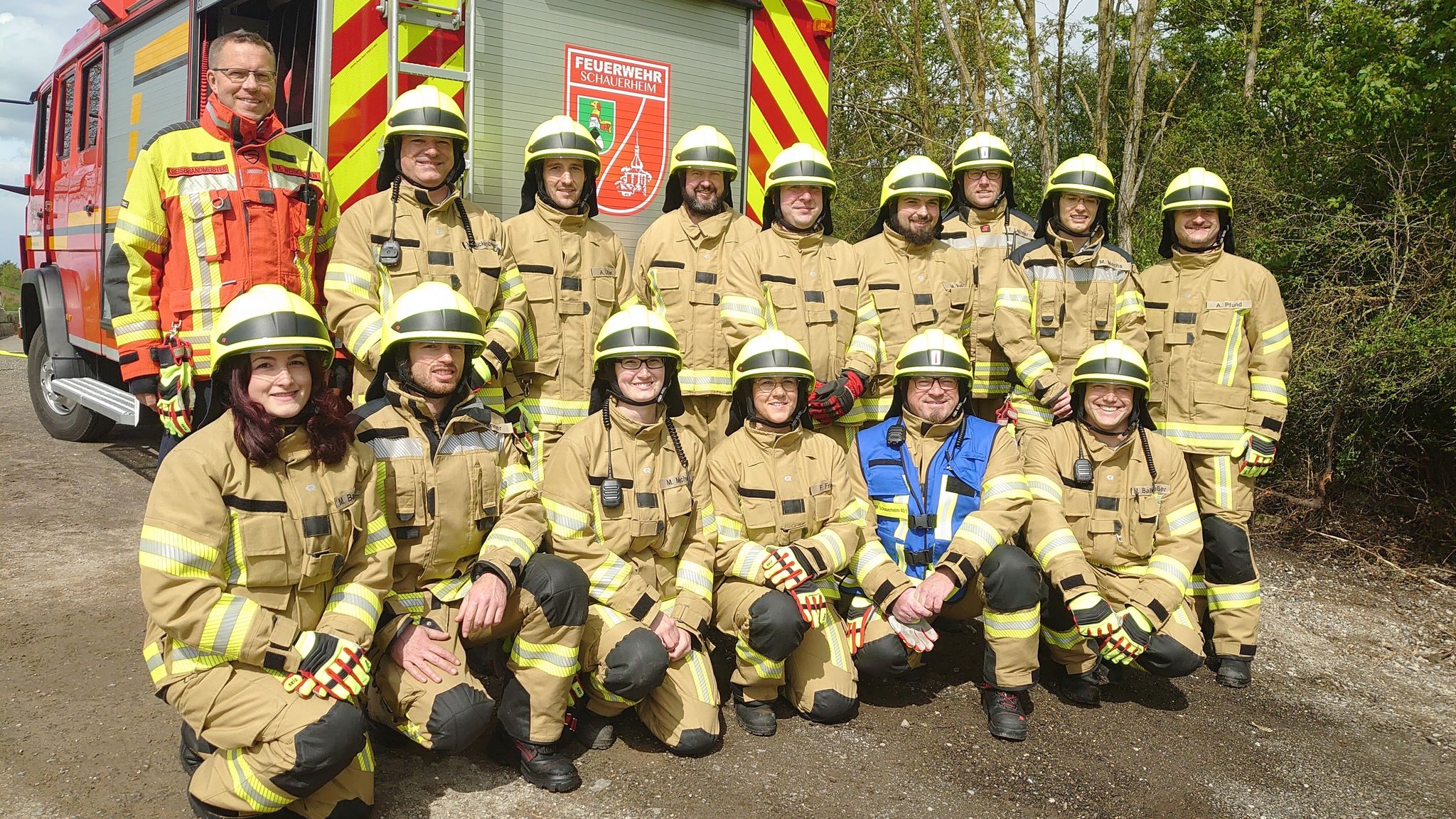 Ein Teil der neuen Feuerwehrtruppe in Schauerheim steht und kniet vor dem Löschfahrzeug  mit dem Namen "Wilhelm".