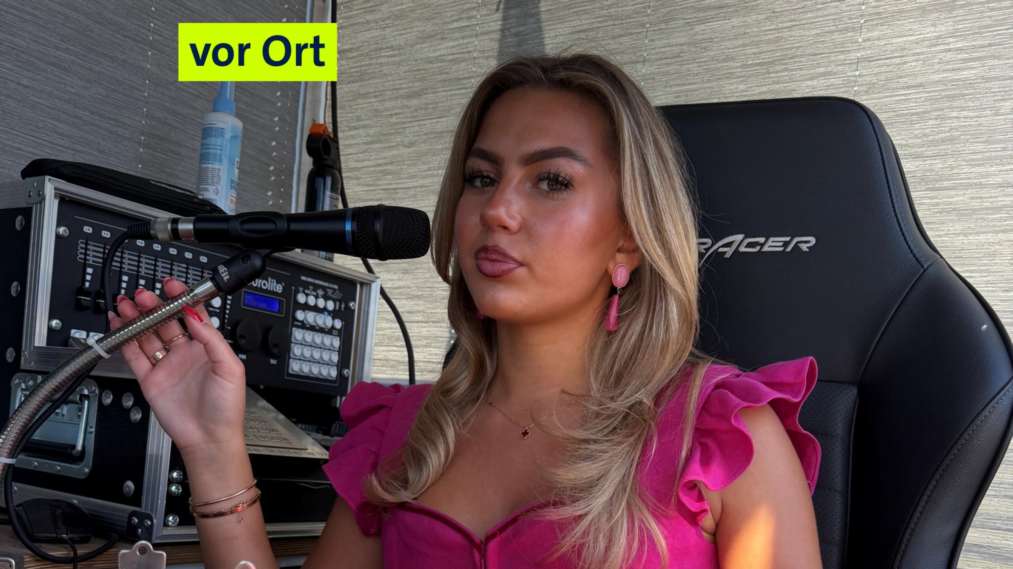 Alisha Kaiser liebt ihren Job: eine Frau mit pinkem Dirndln und kurzen Flügelärmel sitzt auf einem Stuhl vor einem Mirko, hinter hier eine Musikanlage. | Bild: BR/Tanja Gronde Alisha Kaiser liebt ihren Job: eine Frau mit pinkem Dirndln und kurzen Flügelärmel sitzt auf einem Stuhl vor einem Mirko, hinter hier eine Musikanlage.