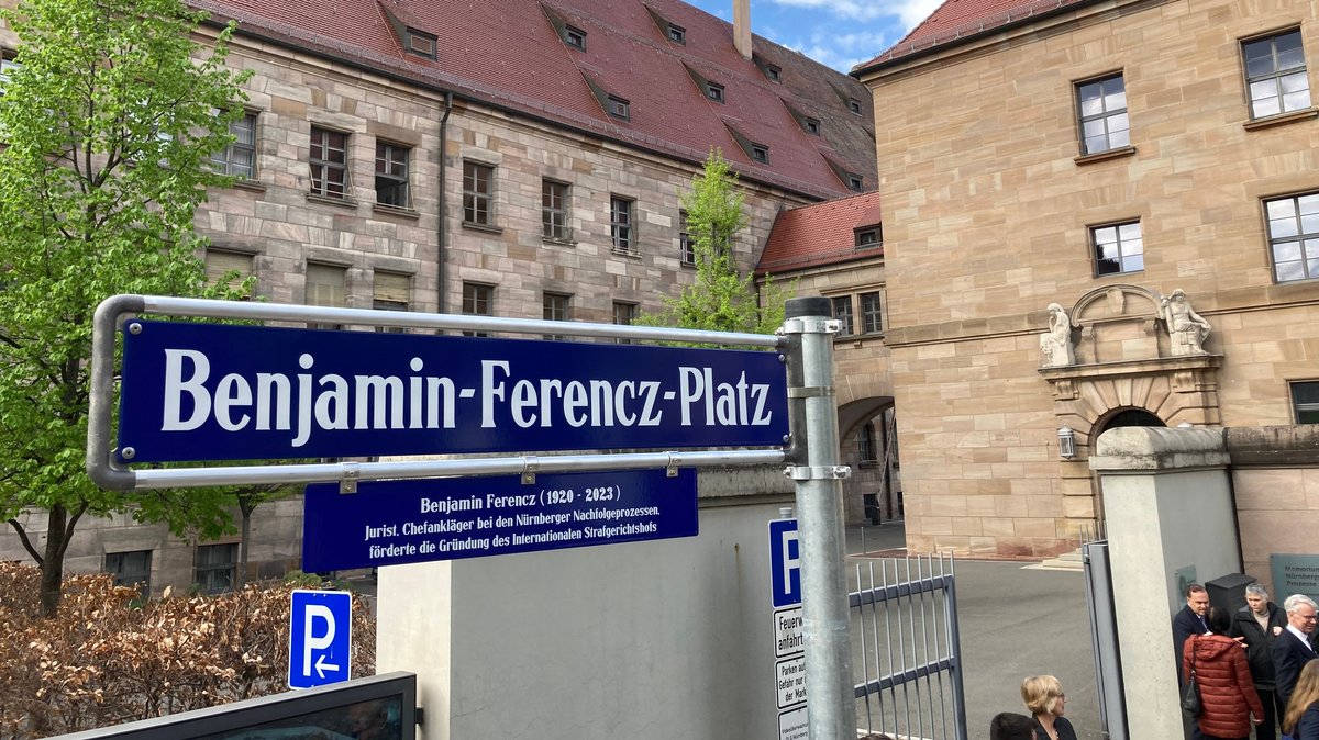 Blaues Straßenschild mit dem Namen Benjamin-Ferencz-Platz. Darunter eine Tafel mit den Lebensdaten von Benjamin Ferencz
