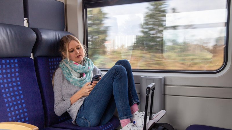 Junge Frau schaut im Zug aufs Handy
