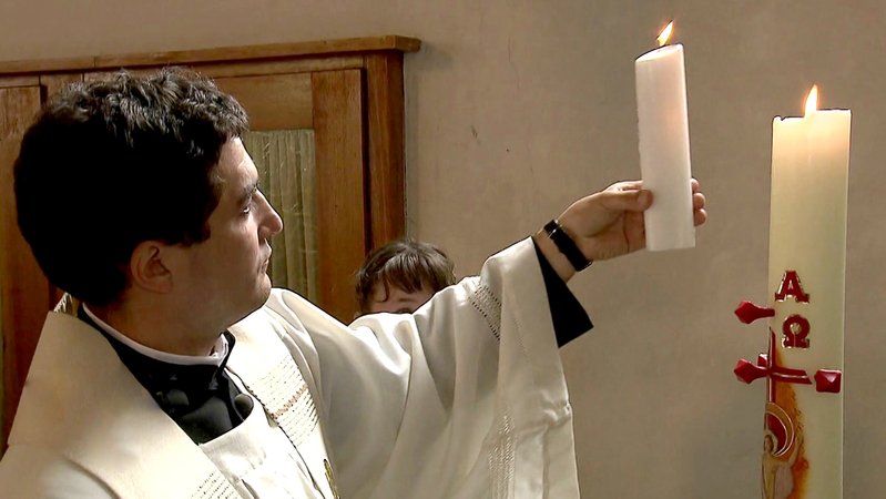 Pfarrer mit Kerze in der Kirche