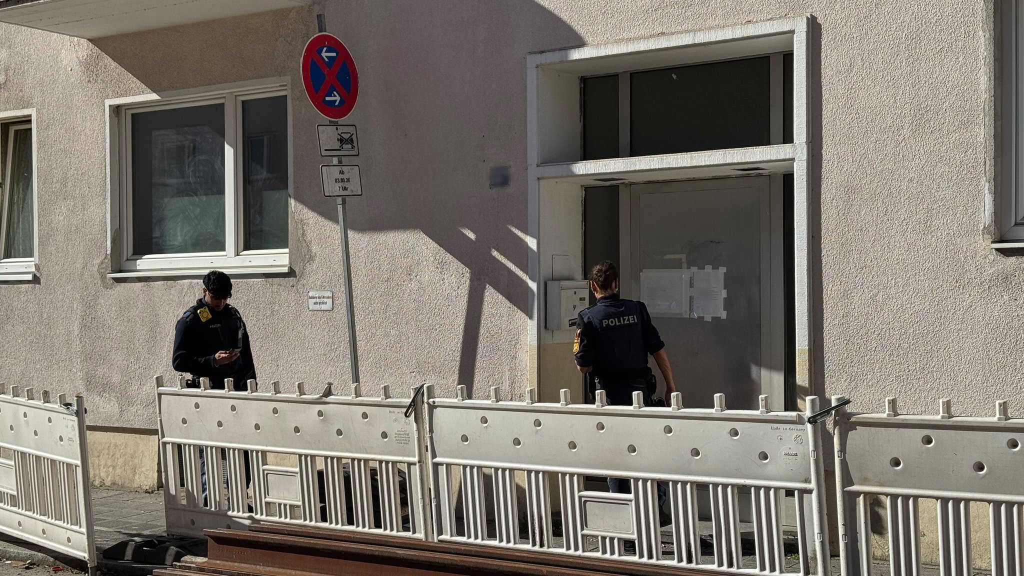 Polizeibeamte stehen vor einem Mehrfamilienhaus. In einer Sozialpension ist nach Polizeiangaben ein 66 Jahre alter Mann tot in seiner Wohnung entdeckt worden. 
