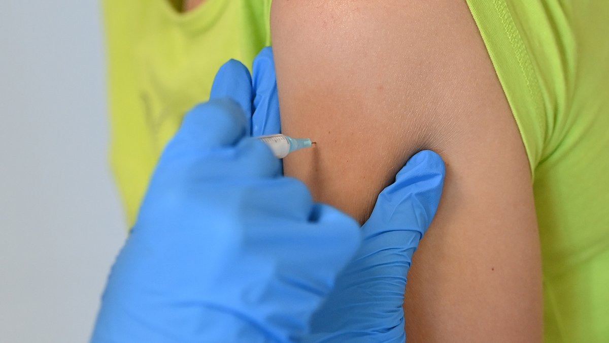 Impfstoff wird mit Impfspritze in den Oberarm gespritzt 