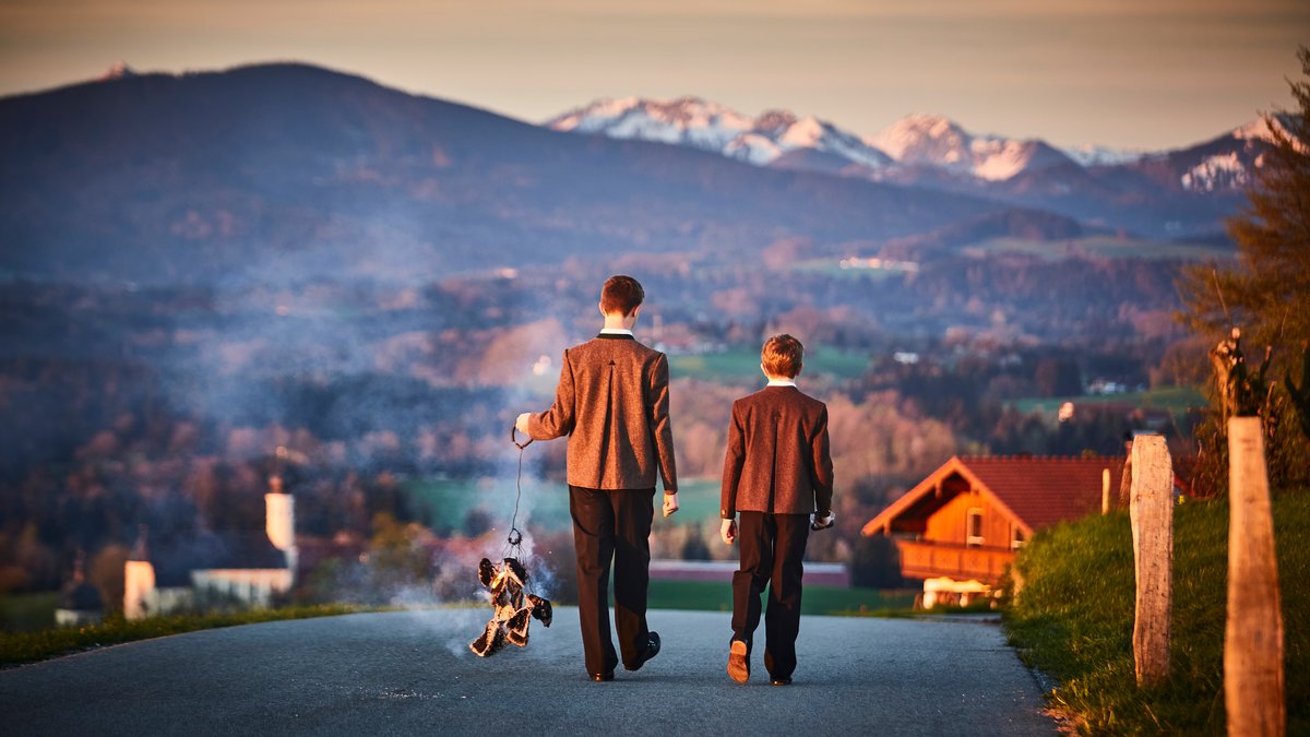 Symbolbild: Zwei Buben laufen mit geweihtem Osterfeuer im bayerischen Irschenberg von Haus zu Haus