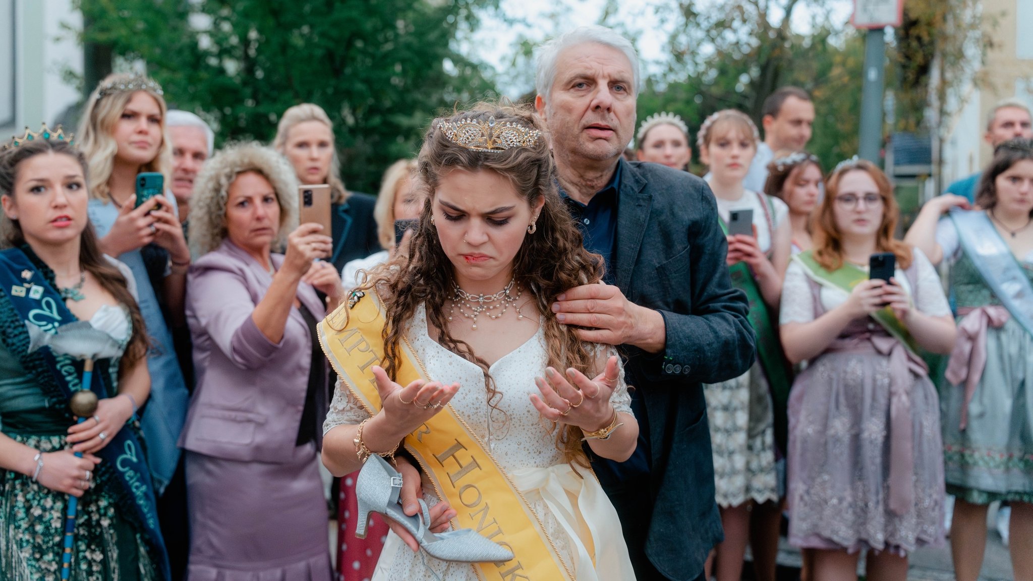 Ein Mann hält eine Frau fest. Sie trägt ein hübsches Kleid und eine Schärpe.