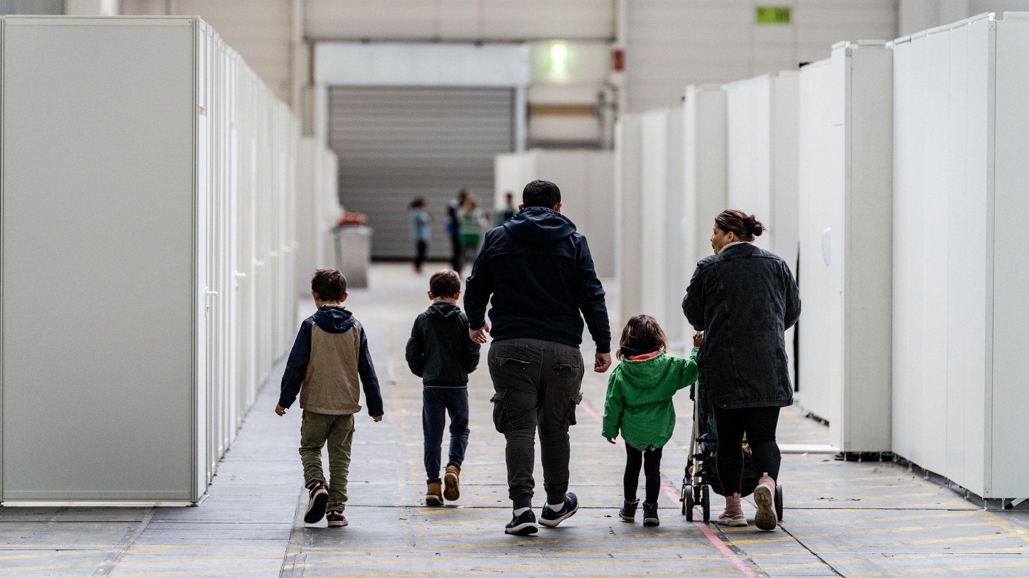 Eine Familie zwischen den für Familien abgeteilten Bereichen einer Flüchtlingsunterkunft in Frankfurt.