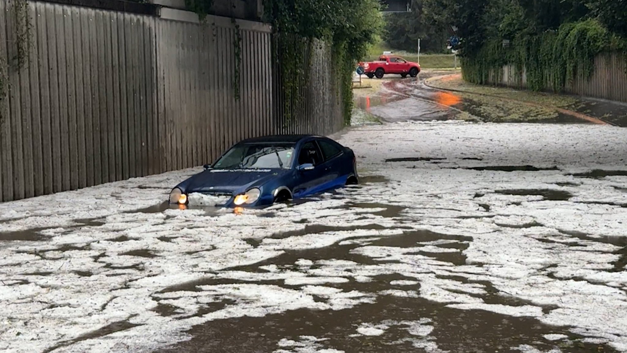 Bayern, Immenstadt: Nach schweren Unwettern steht ein Auto auf einer überfluteten Straße.