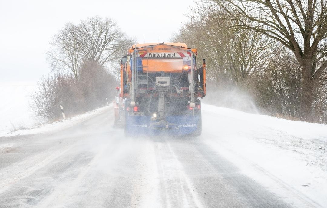 Symbolbild Unwetter im Winter. 09.01.2026, Schleswig-Holstein, Haffkrug: Ein Fahrzeug vom Winterdienst fährt bei Schneeve