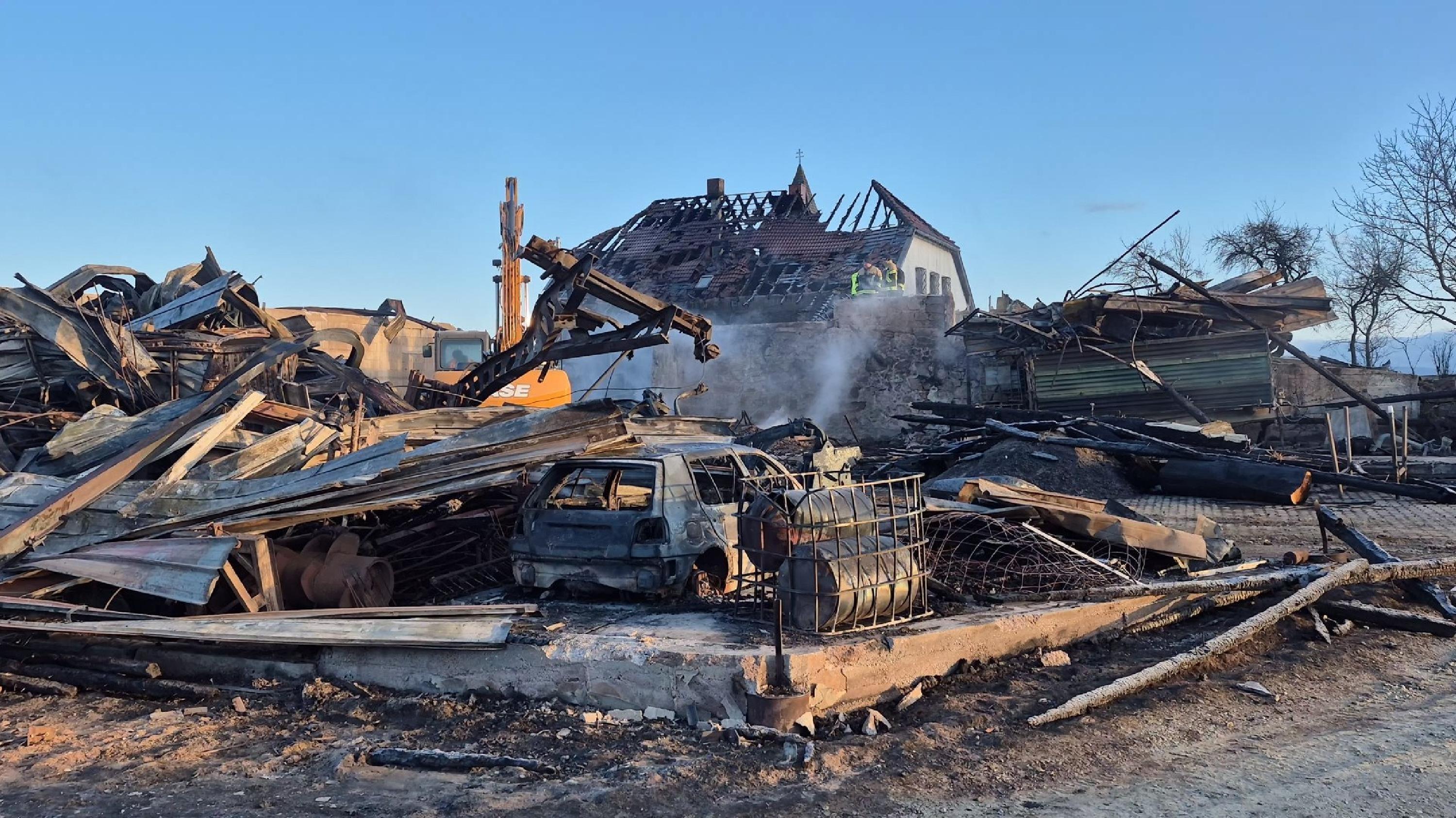 Das beschädigte Wohnhaus, ein ausgebranntes Auto und viele Trümmer nach dem Brand auf dem Bauernhof.