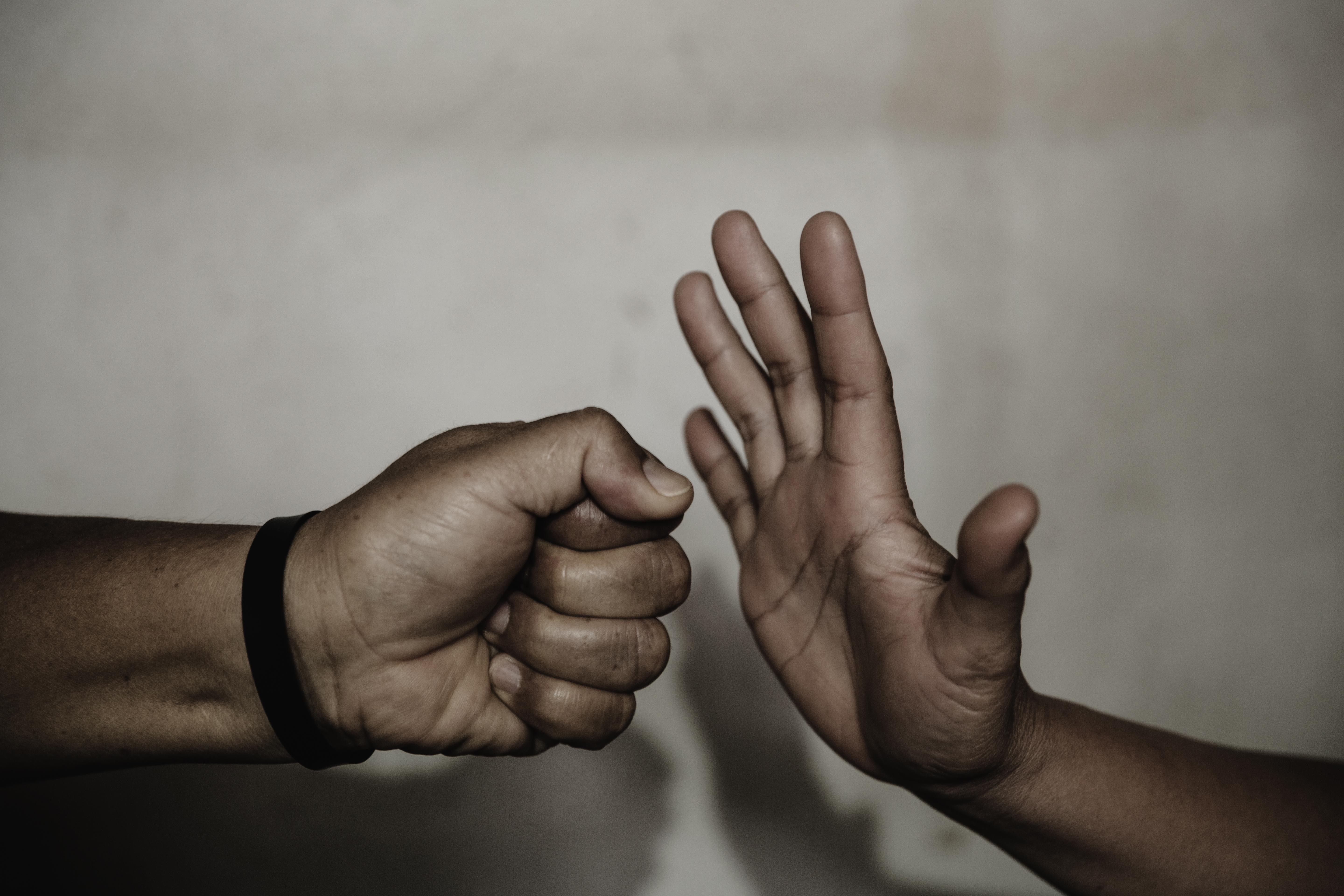 Eine Faust und eine abwehrende Hand als Symbol für weniger Gewalt.