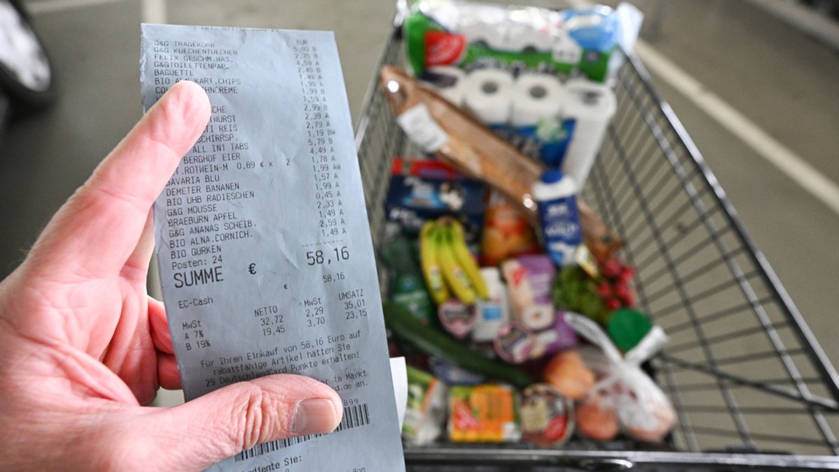 Ein Verbraucher hält nach einem Einkauf in einem Supermarkt einen Kassenzettel in der Hand.