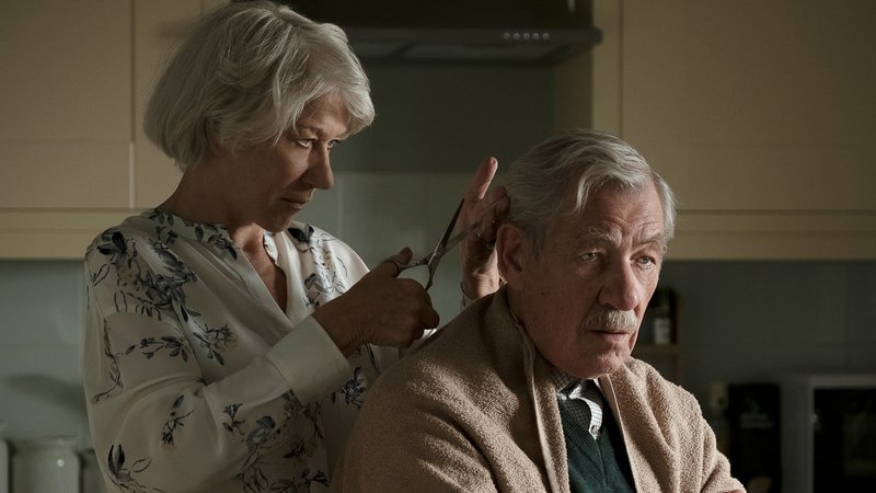 Eine ältere Frau schneidet einem älteren Mann in der Küche die Haare.