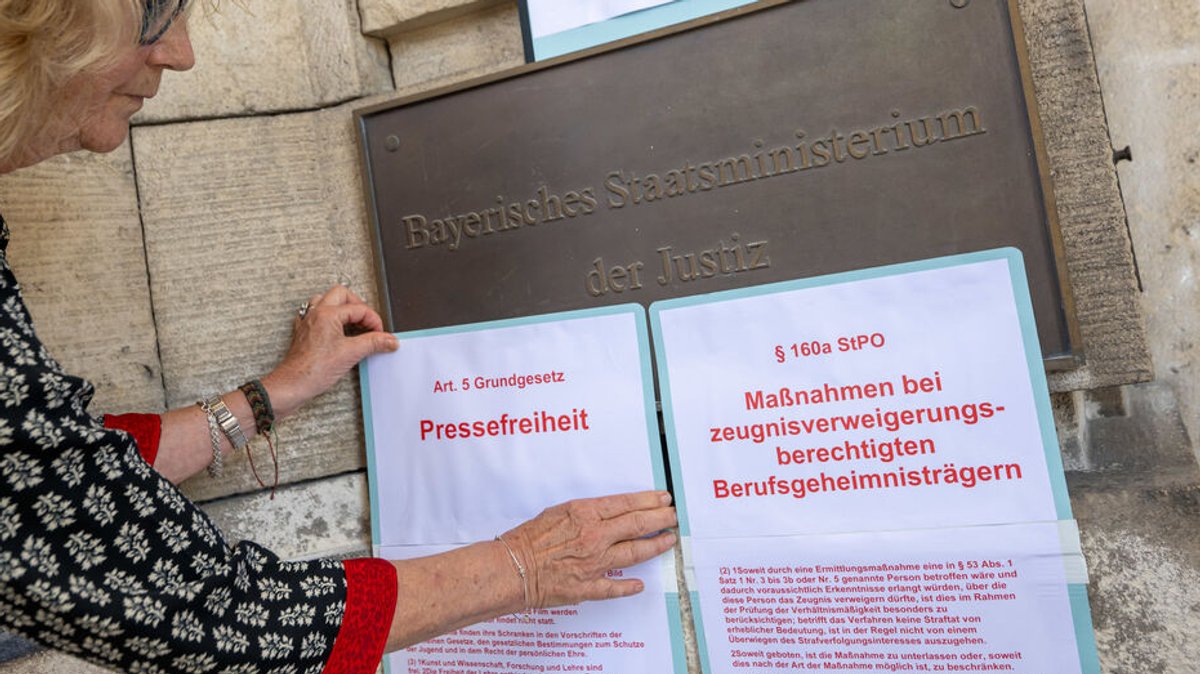 25.06.2023, Bayern, München: Gesetzestexte werden von einer Frau bei einer Protestaktion am Eingang des Justizministerium in der Innenstadt angebracht. 